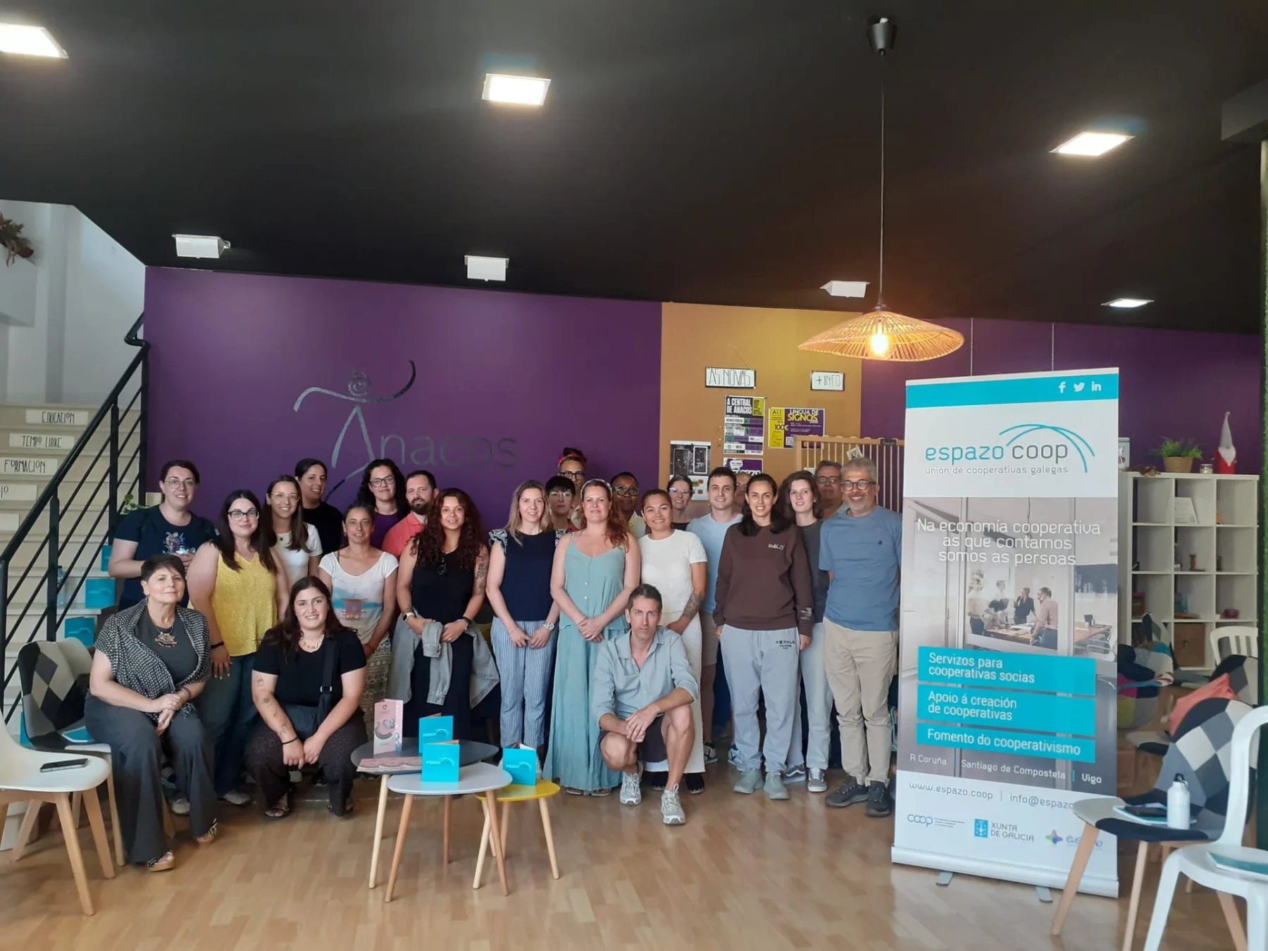 Group photo of people taking part in Xornada +Coop next to the EspazoCoop roll-up banner.