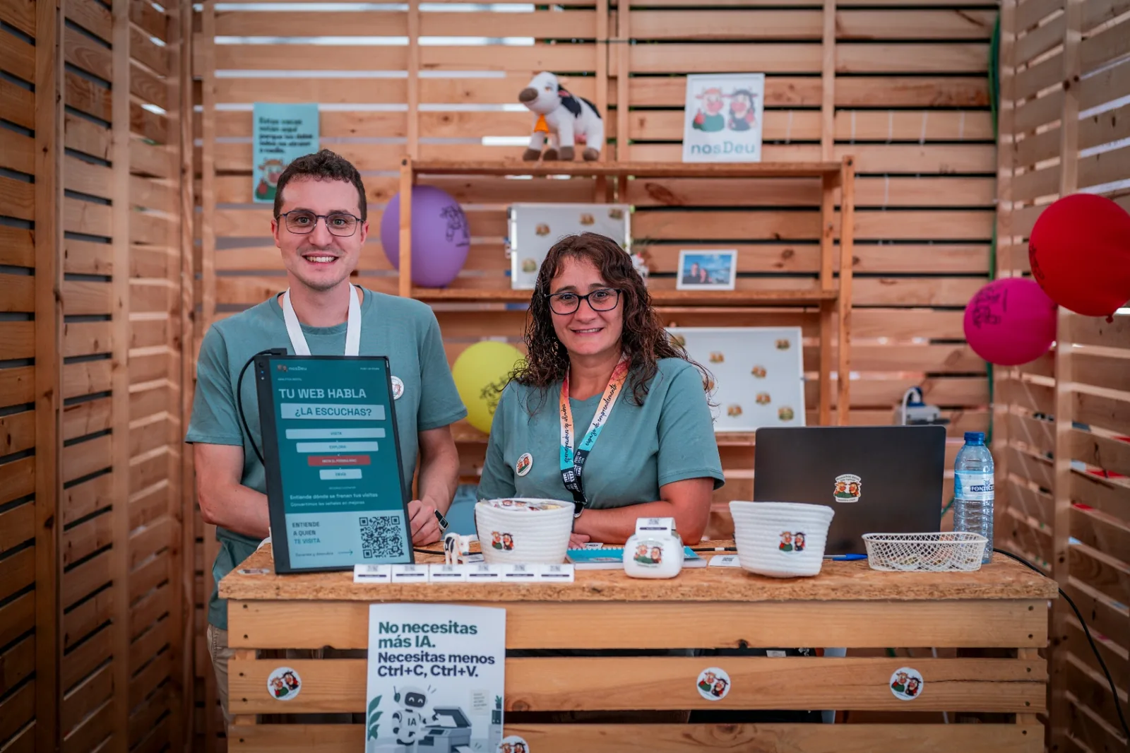 Brais and Eva standing at the nosDeu stand with the interactive display and merch